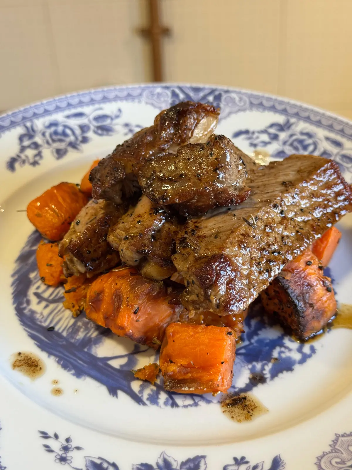 Carne estufada com legumes assados num prato de faiança azul e branca.
